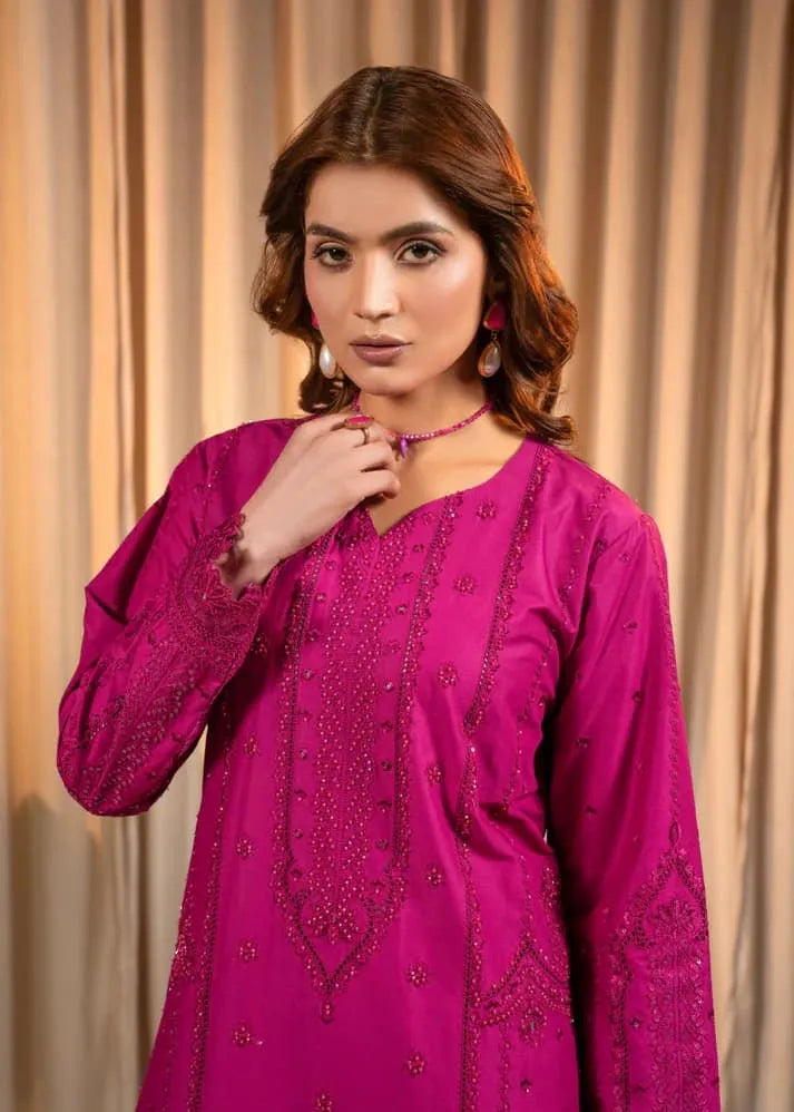 Woman wearing a pink embroidered traditional outfit against a beige curtain background