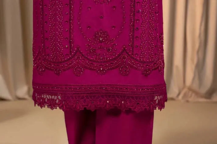 Close-up of a magenta embroidered garment with intricate patterns on a neutral background