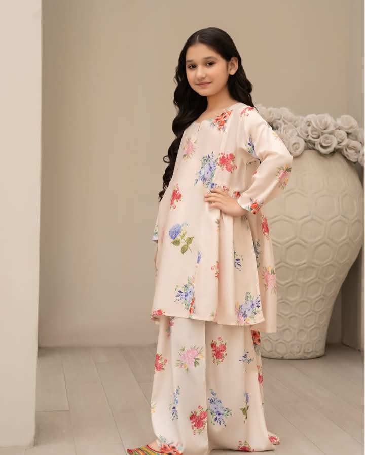 Young girl wearing a floral outfit standing against a neutral background