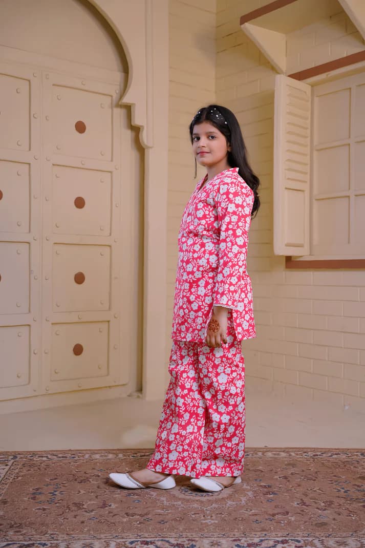 Person wearing a pink floral outfit standing in a room with beige walls and a patterned rug.
