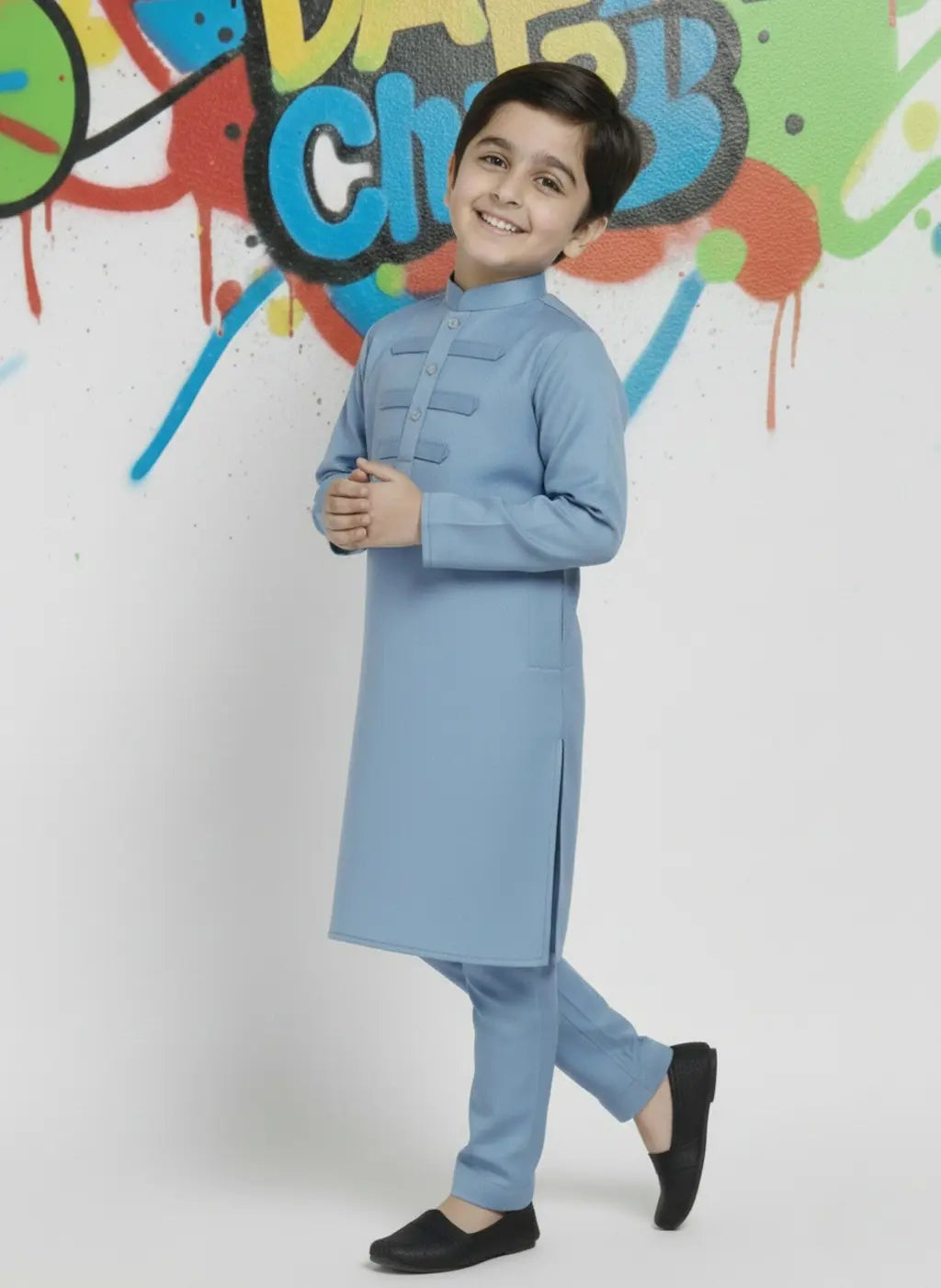 Child wearing a light blue kurta with a colorful graffiti wall in the background