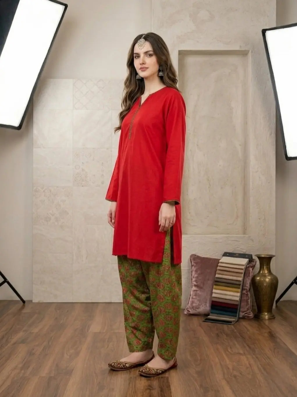 Woman wearing a red kurta with green printed shalwar in a studio setting