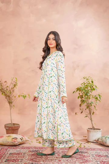 Woman in a floral dress standing in front of a pink wall with plants and pillows.