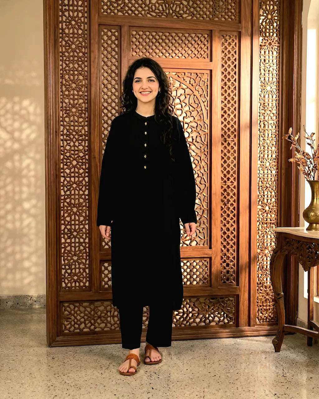 A girl in a black outfit standing in front of a wooden carved screen