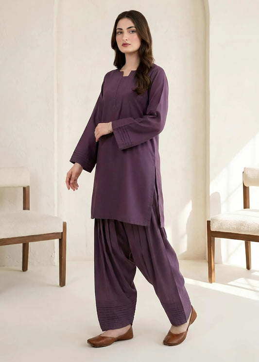Woman wearing a purple outfit in a minimalistic room with white walls and chairs.