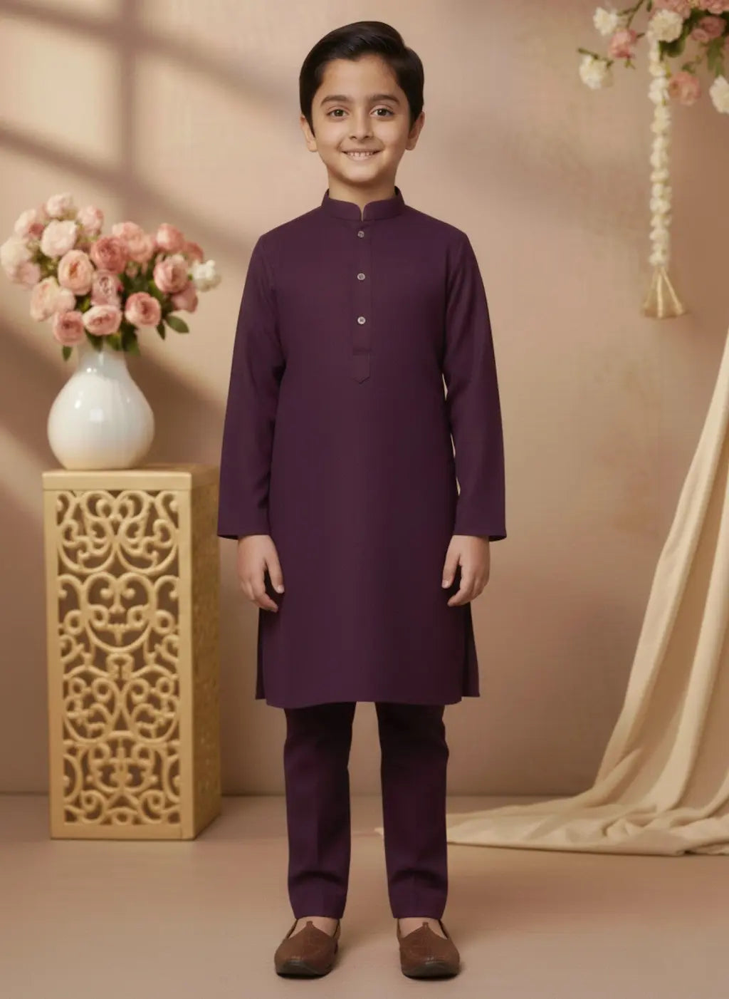 Young boy in a purple kurta standing in a decorated room with flowers and a vase.