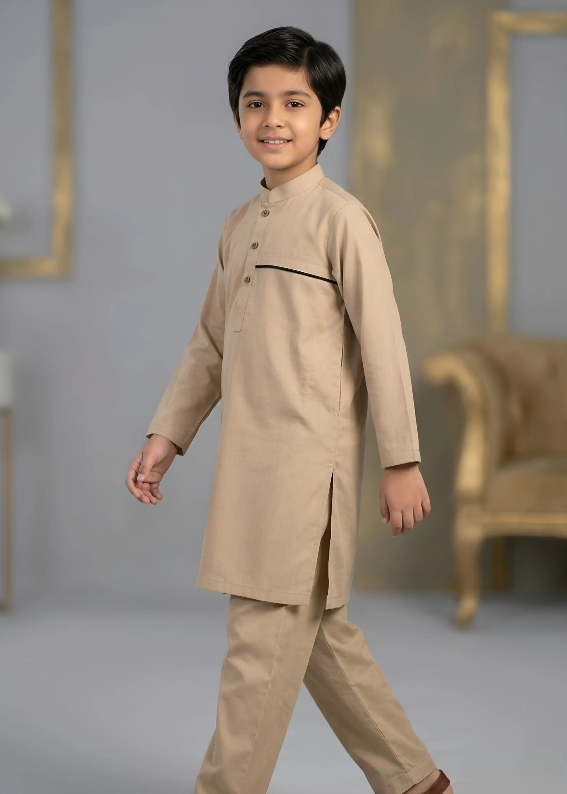 Young boy wearing a beige kurta with a plain background