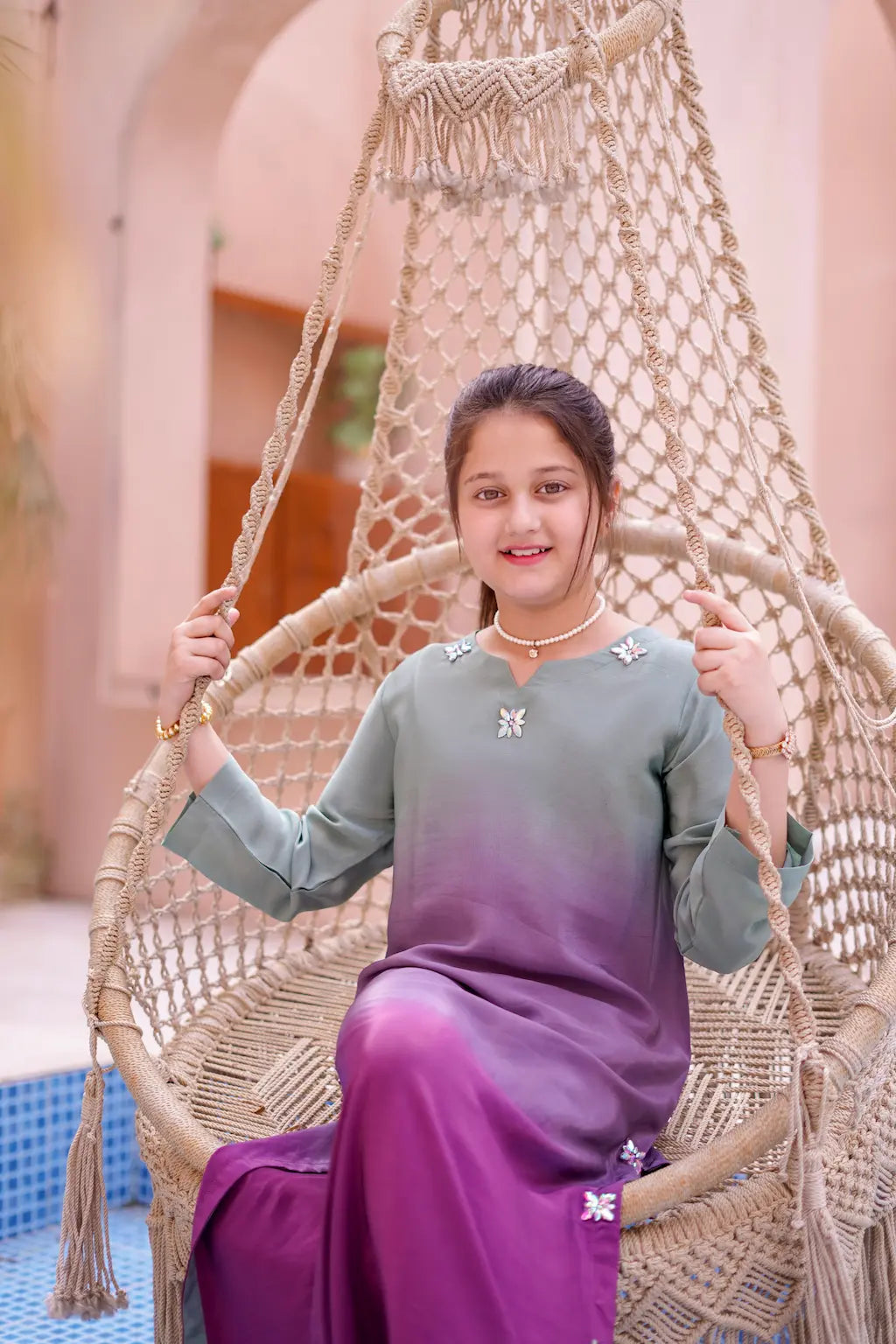Young girl sitting on a woven chair in an outdoor setting