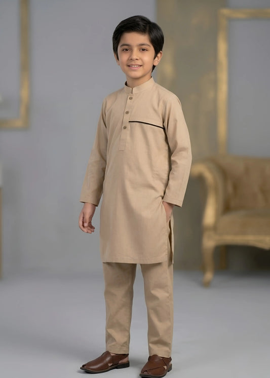 Young boy wearing a beige kurta with brown shoes in a studio setting