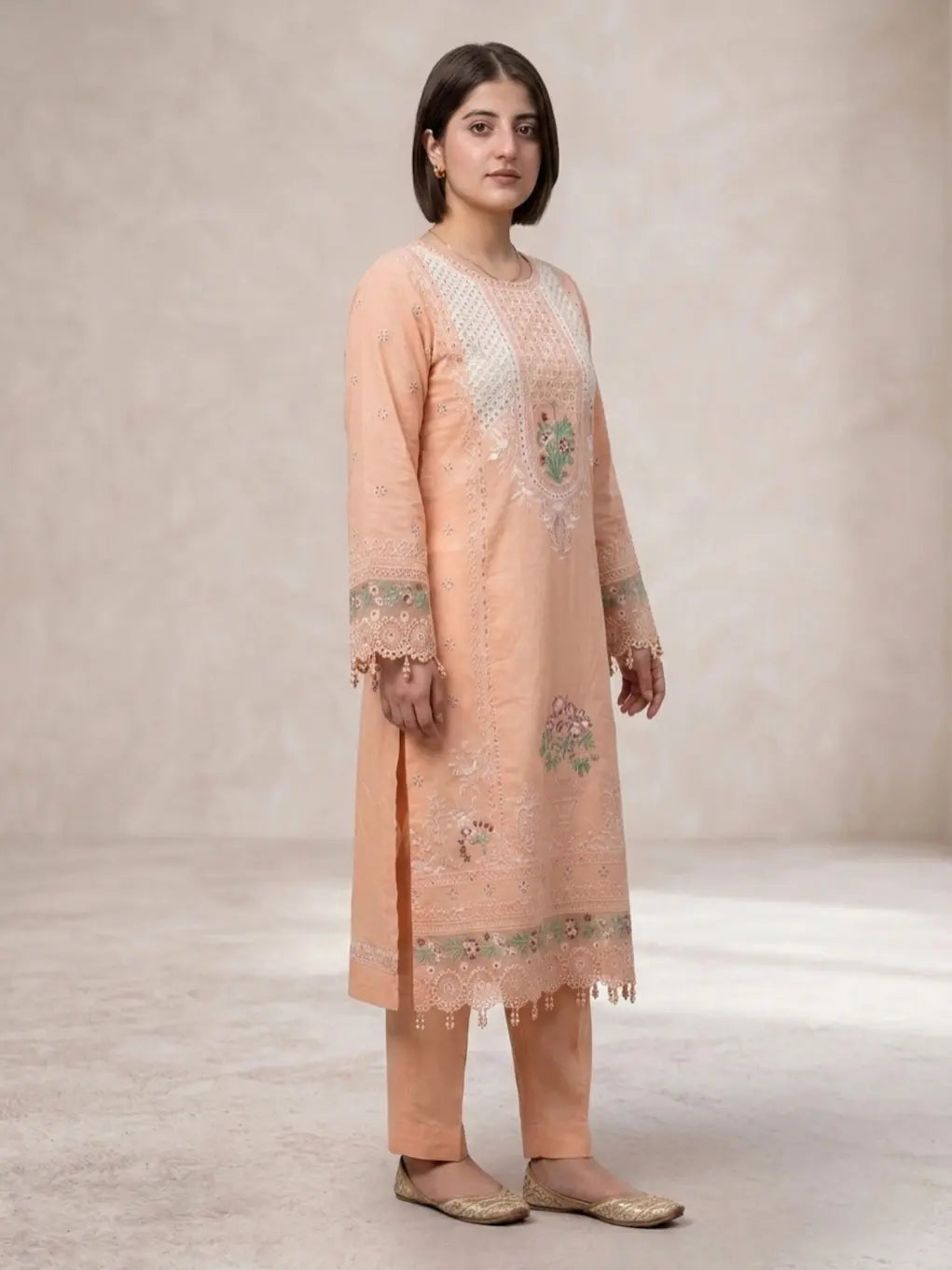 Woman wearing a peach embroidered kurta with pants on a neutral background