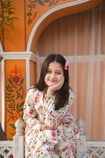 Young girl in a floral dress posing against an ornate wall.