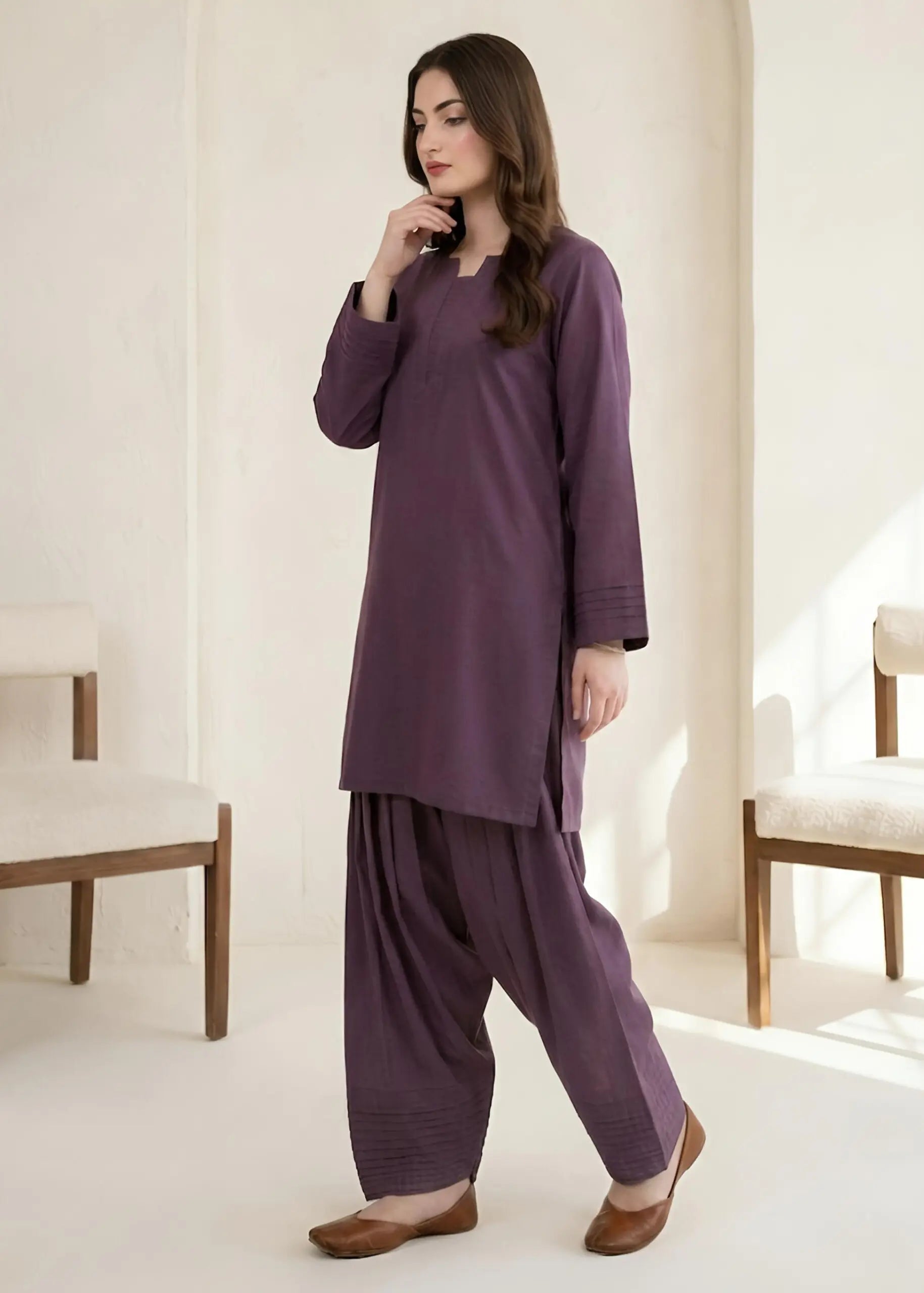 Woman wearing a purple traditional outfit in a minimalistic room.