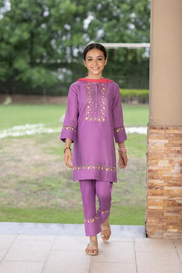 Girl in a purple traditional outfit standing outdoors with greenery in the background