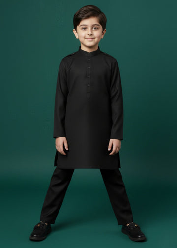 Young boy wearing a black kurta and pants against a green background