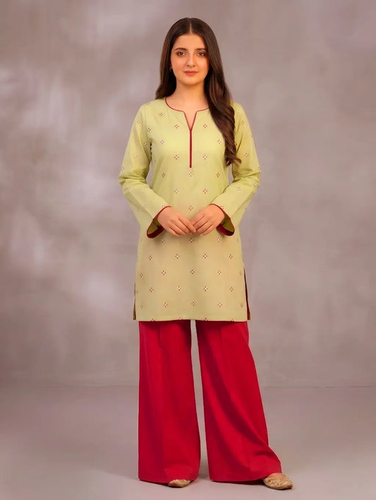Woman wearing a light green kurta with red pants against a gray background