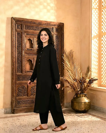 A girl in a black outfit standing in a room with decorative elements