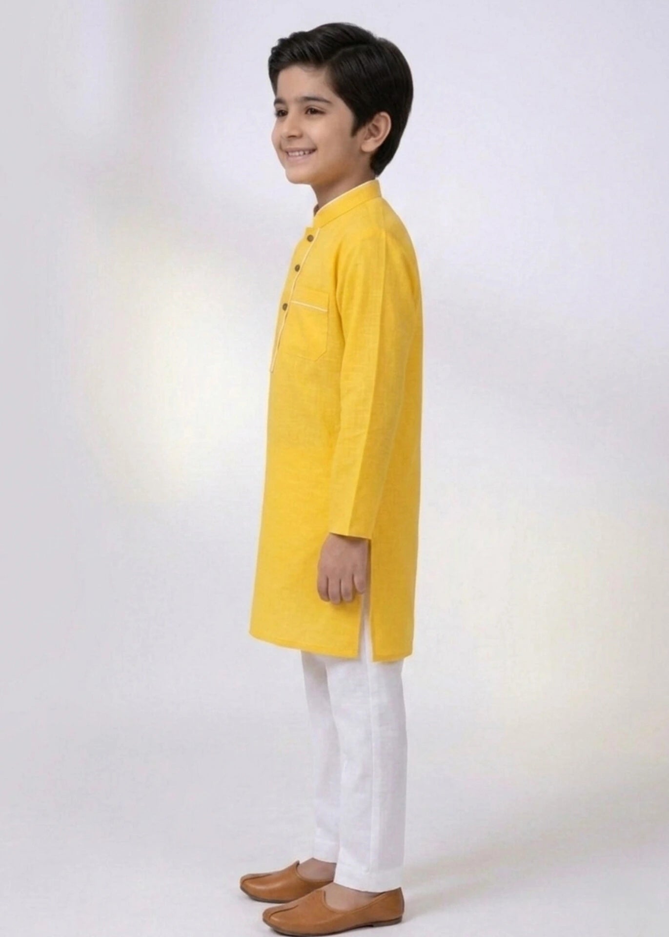 Child wearing a yellow kurta with white pants on a white background