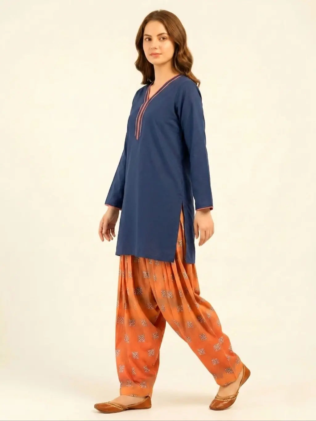 Side profile of a model showcasing a navy blue short lawn shirt with side slits and a digital printed rust-colored Farshi shalwar, finished with traditional brown leather khussas.