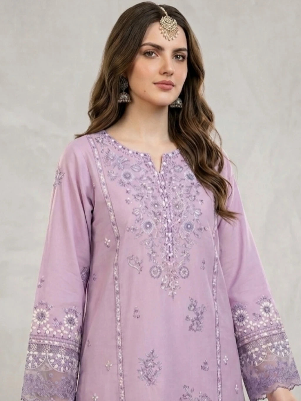 Woman wearing a light purple embroidered dress against a plain background