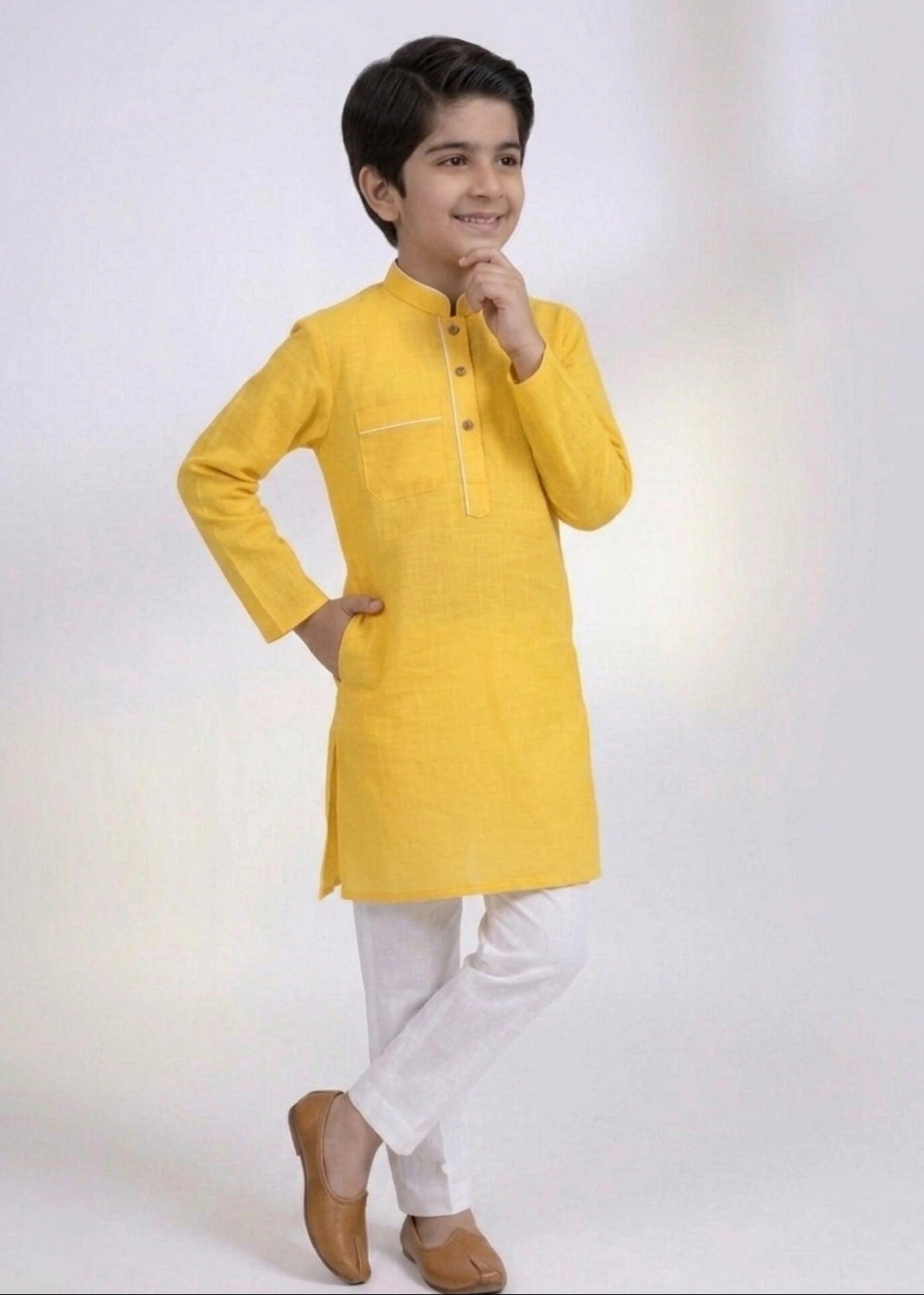 Child wearing a yellow kurta with white pants on a light gray background