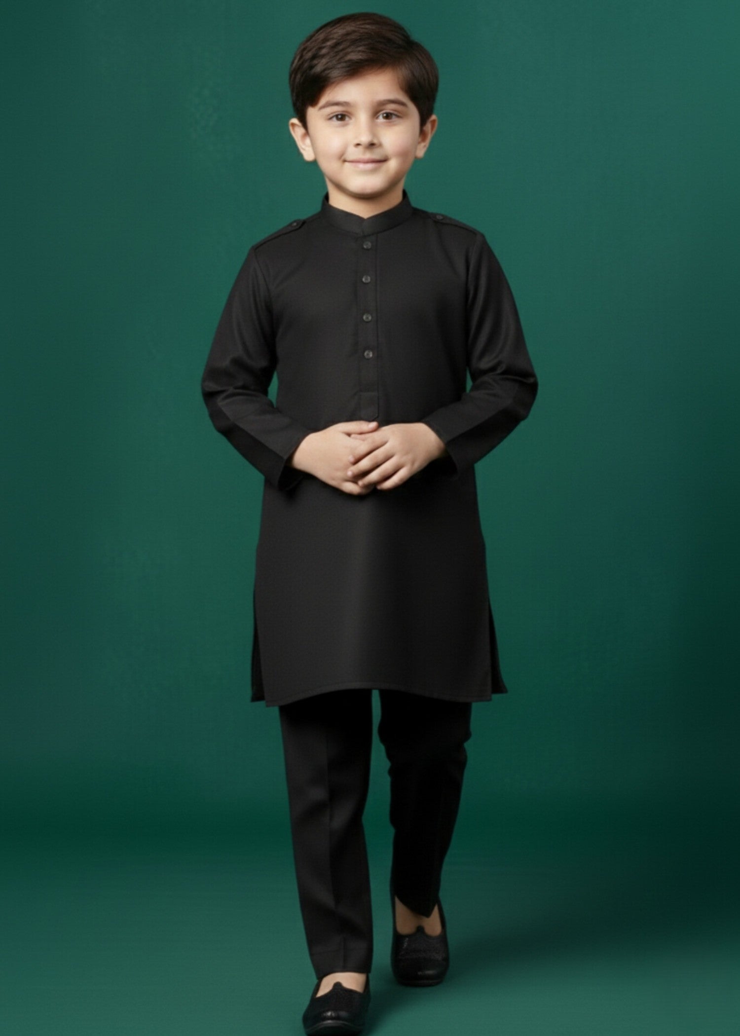 Young boy wearing a black kurta with black pants on a green background