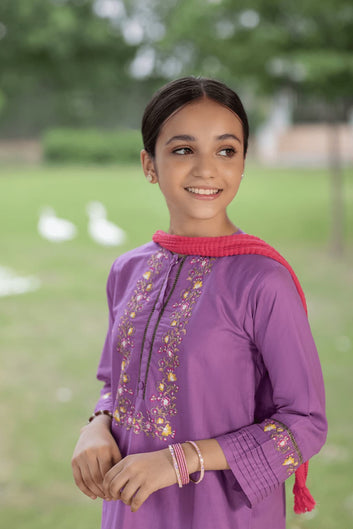 Young girl wearing a purple embroidered top with a pink shawl in an outdoor setting.