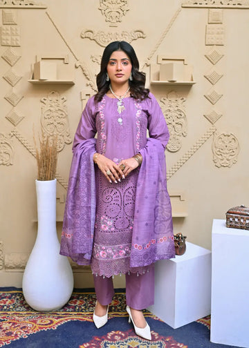 Woman in a purple embroidered outfit standing in a decorated room with a textured wall.