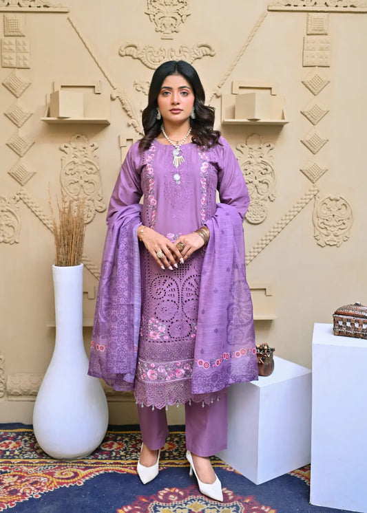 Woman in a purple embroidered outfit standing in a decorated room with a textured wall.