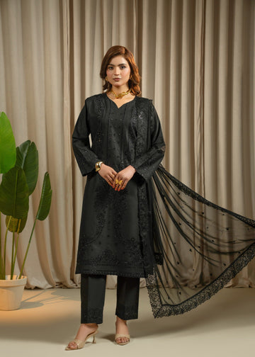 Woman in a black traditional outfit with a long black scarf against a beige curtain background