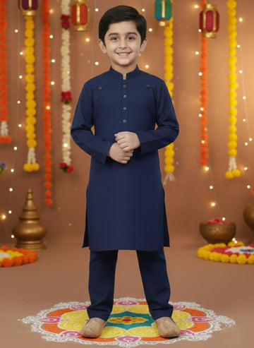 Young boy in a navy blue kurta standing in front of decorative lights and rangoli
