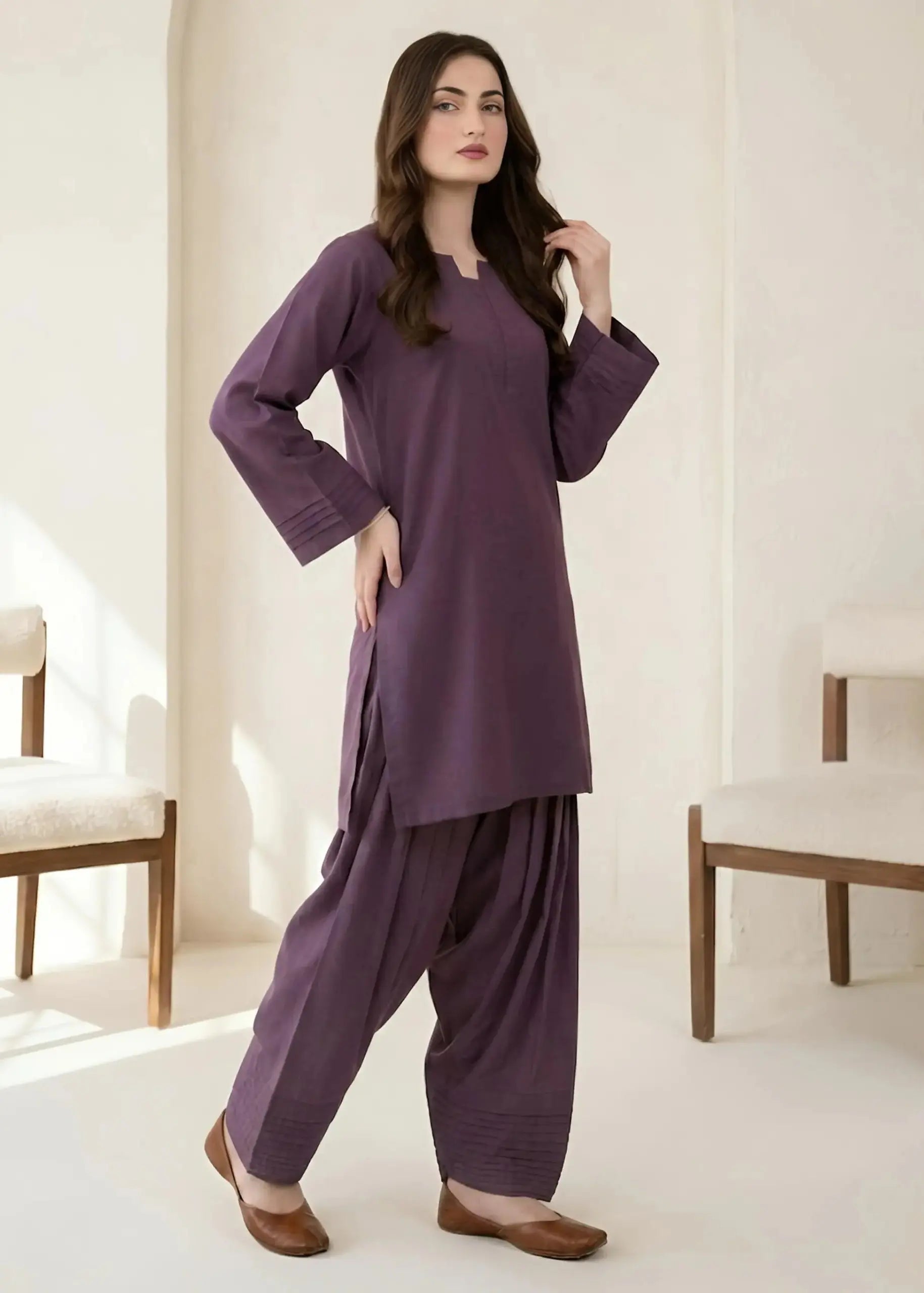 Woman wearing a purple traditional outfit in a minimalistic room.