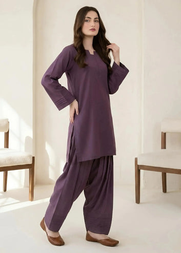 Woman wearing a purple traditional outfit in a minimalistic room.