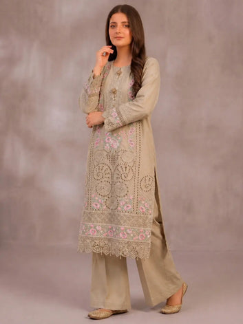 Woman wearing a beige embroidered traditional outfit against a plain background