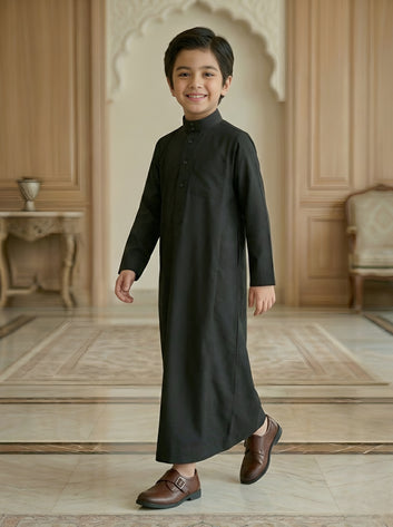 Young boy wearing a black traditional outfit in an elegant room.