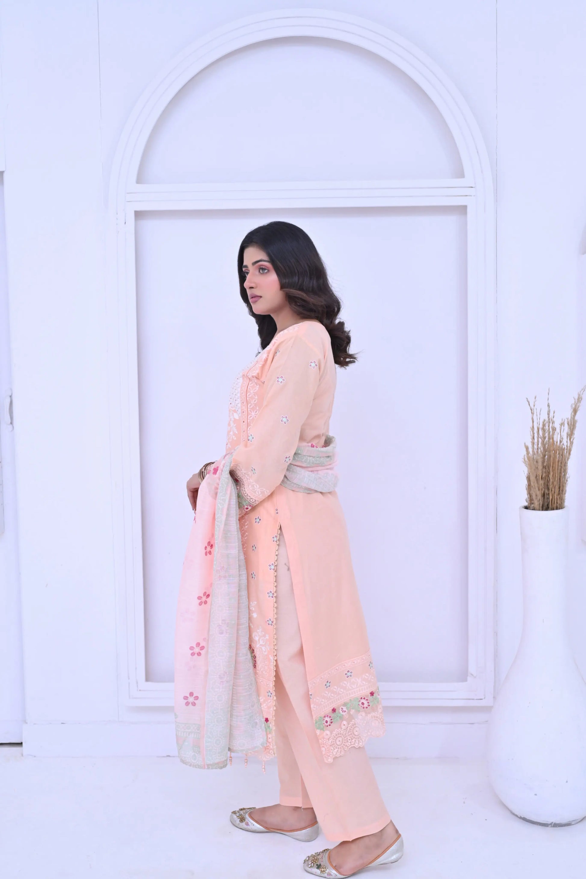Woman in a peach traditional outfit with a white background