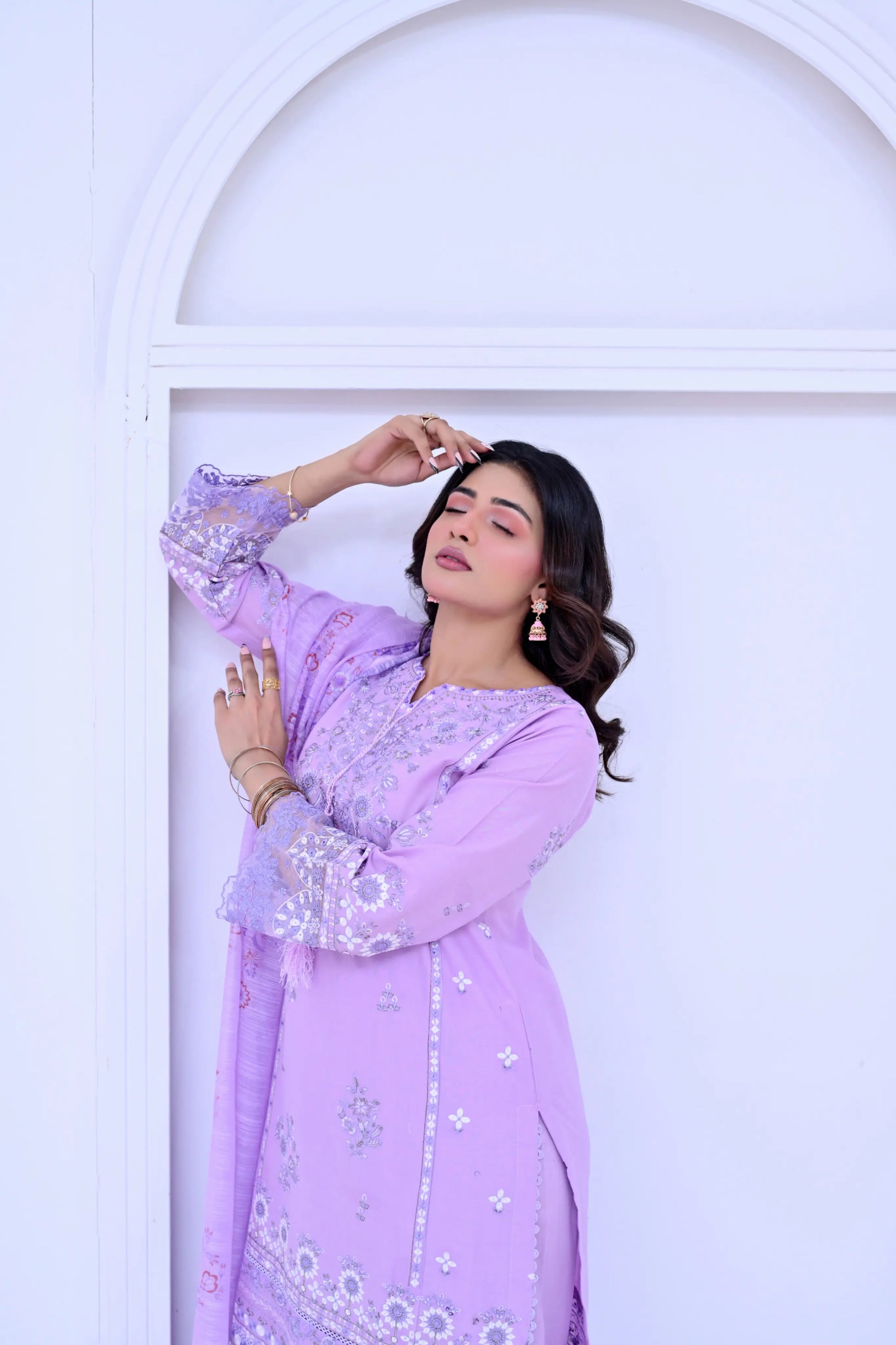 Woman in a light purple traditional outfit posing against a white background