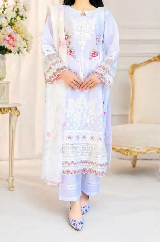 A woman posing in a 3-piece white embroidered cotton lawn suit. The outfit features pink floral embroidery on the shirt, organza cutwork sleeves, and a heavy lace border on the daman. Paired with straight-cut trousers and a printed floral dupatta. Perfect for summer fashion and festive wear.