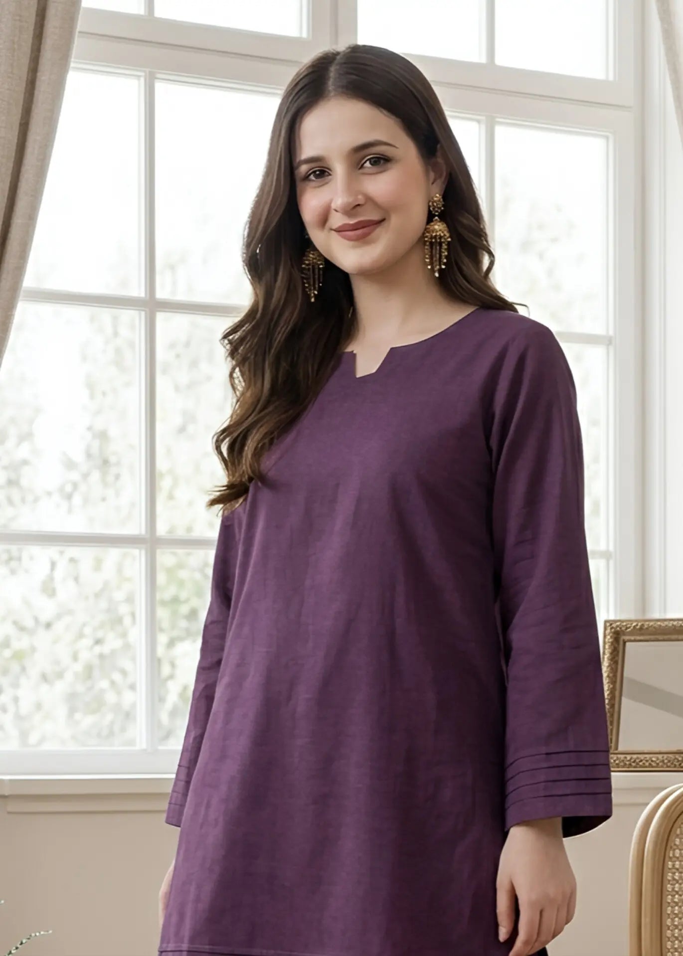Woman wearing a purple dress standing in a room with large windows.