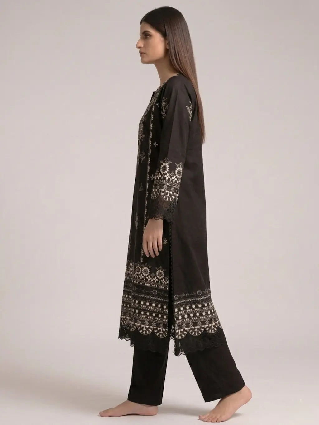 Woman wearing a black embroidered outfit on a plain background