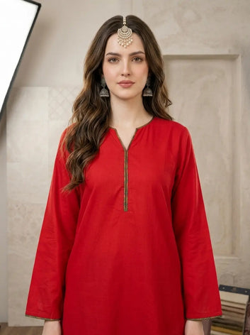 Woman wearing a red kurta with gold details against a neutral background