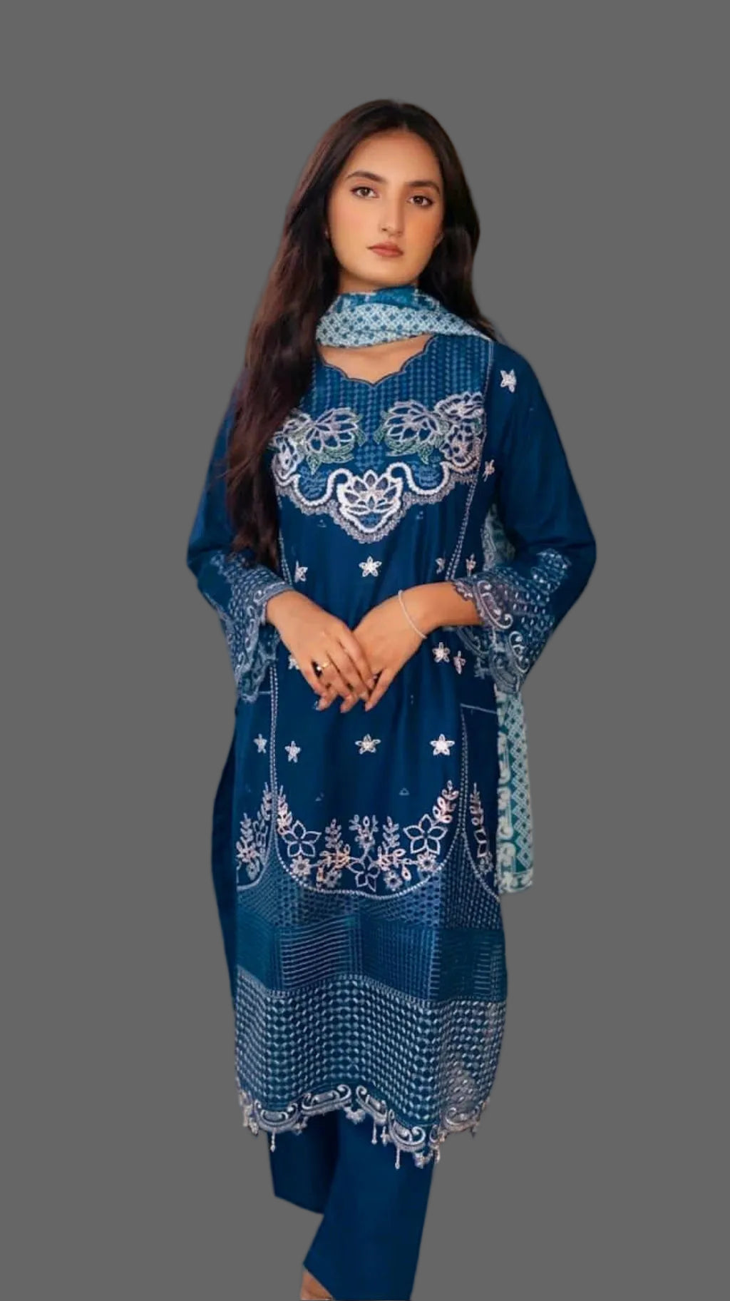 Woman wearing a blue embroidered outfit with a matching scarf against a neutral background