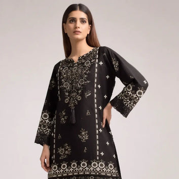 Woman wearing a black embroidered dress on a plain background