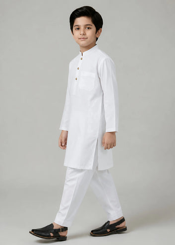 Young boy wearing a white traditional outfit on a plain background