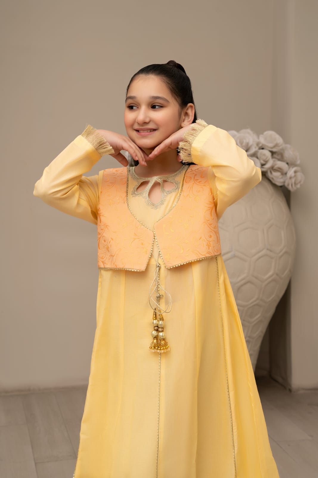 Woman wearing a yellow traditional outfit with a matching jacket indoors.