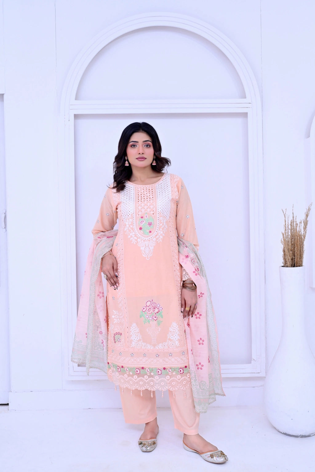 Woman wearing a peach-colored traditional outfit with floral patterns against a white background