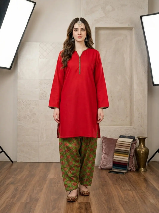 Woman wearing a red kurta with green printed shalwar in a studio setting