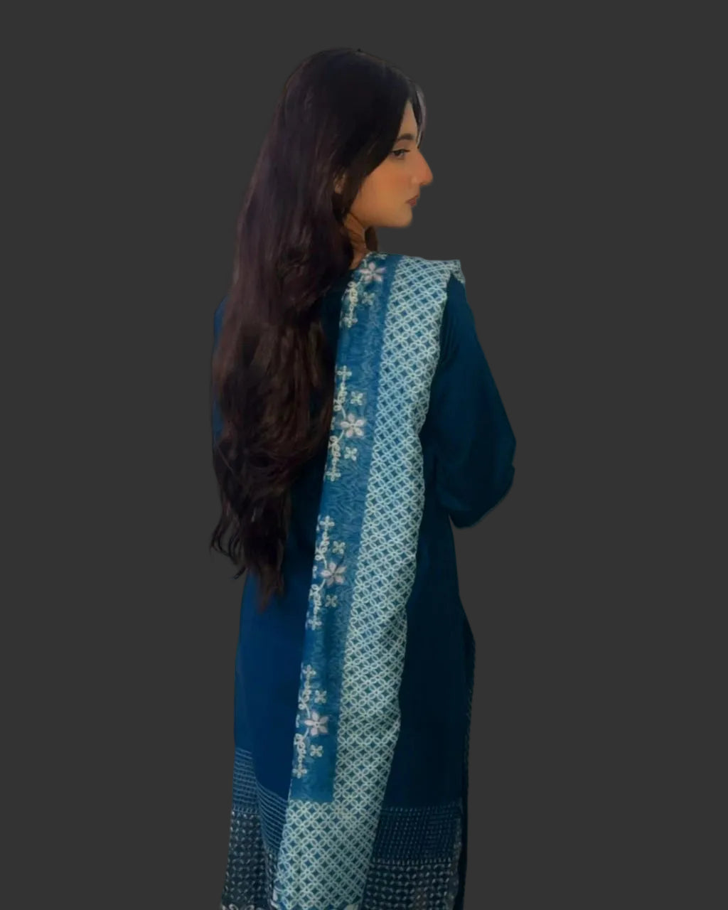 Woman wearing a blue traditional outfit with a matching scarf against a white curtain background