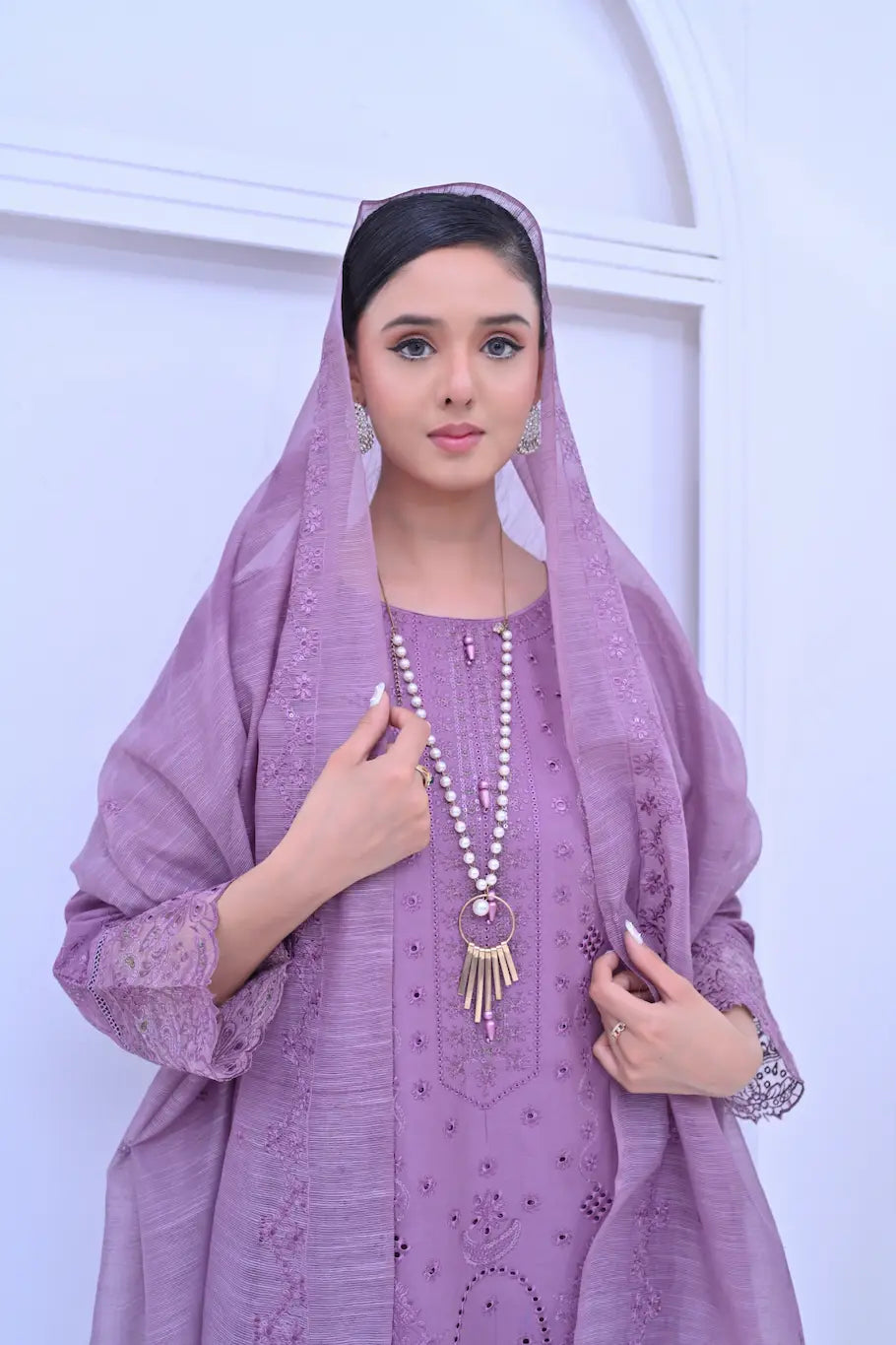 Close-up of a woman in a lavender embroidered suit with a sheer dupatta draped over her head.