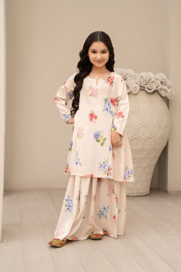 A young girl wearing a traditional cream-colored silk lehnga with floral prints, consisting of a long-sleeve top and a flared skirt.