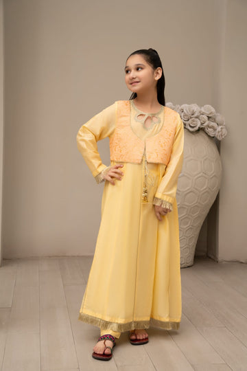 A girl wearing a yellow long jacket attached to a matching shirt, with trousers, posing against a neutral background.